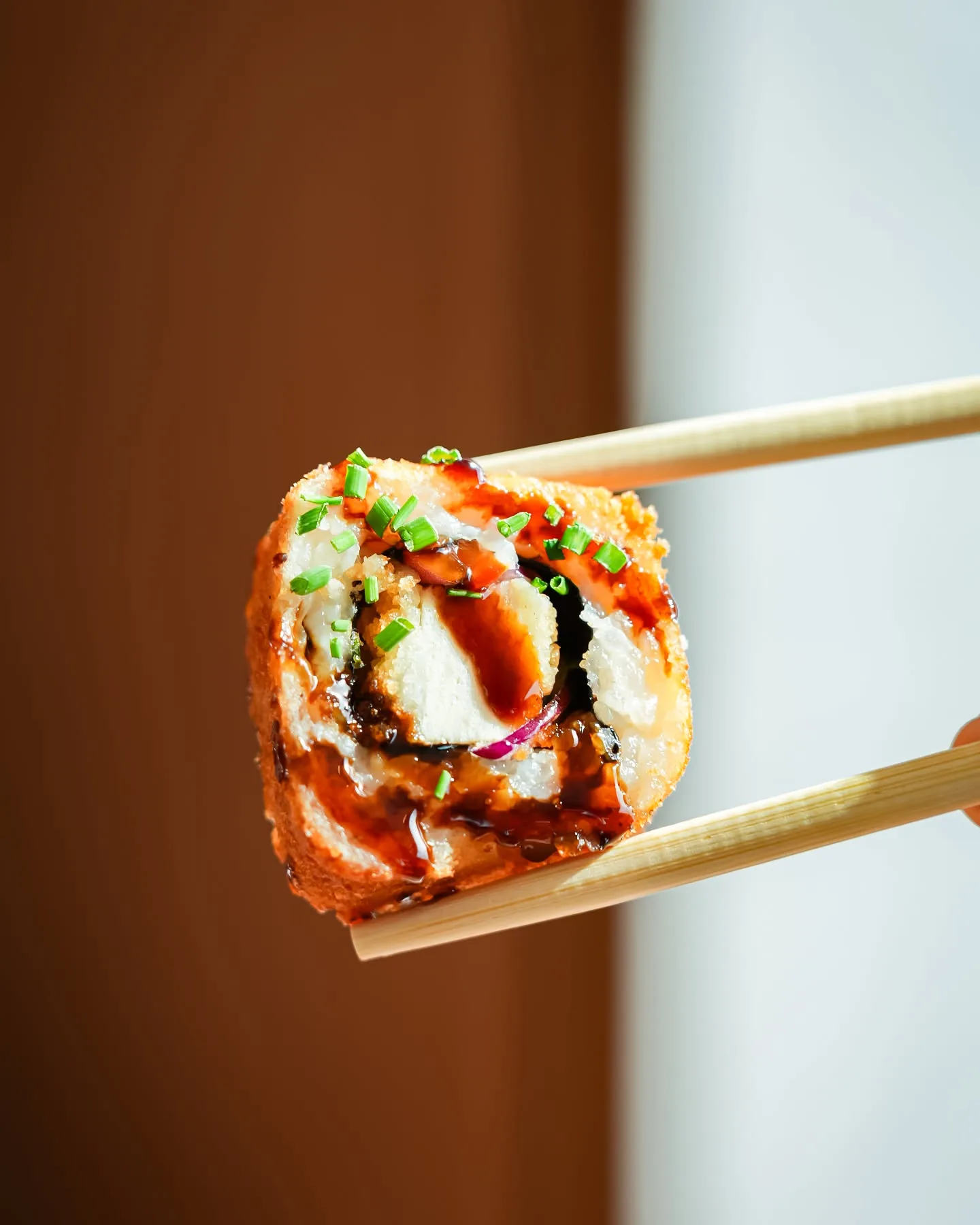 Roll crispy nappé de sauce teriyaki saisi aux baguettes chez Sushi Wa, Place Flagey